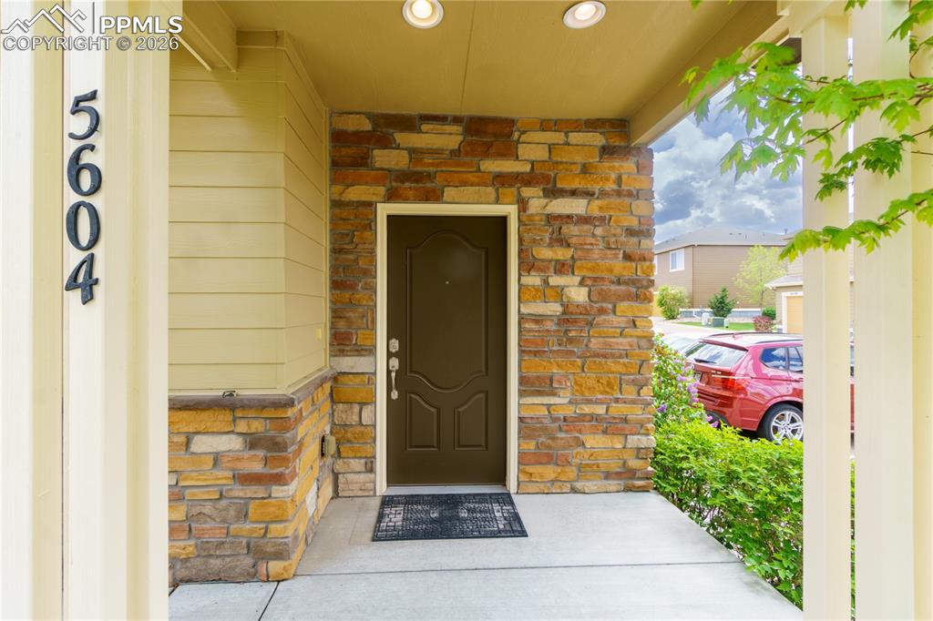 Image 5 of 33: Doorway to property with stone siding and covered porch