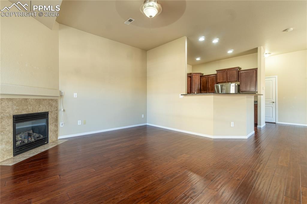 Image 7 of 33: Unfurnished living room featuring a fireplace, dark wood-style floors, ceil