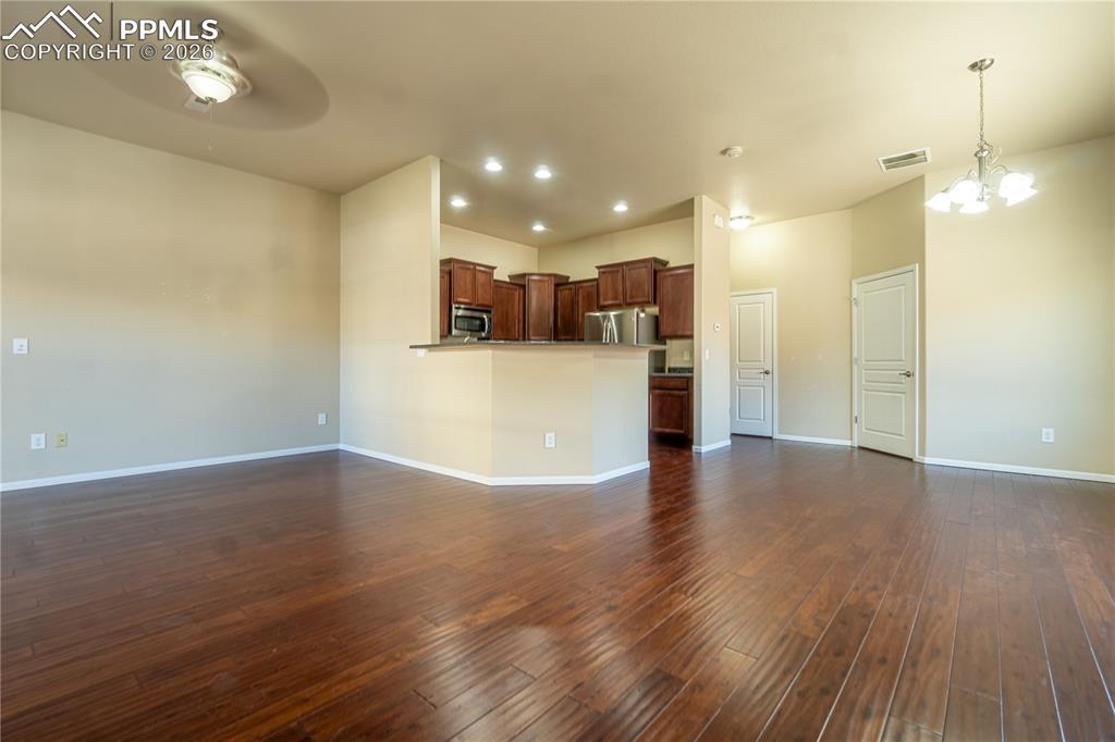 Image 8 of 33: Unfurnished living room featuring dark wood finished floors, a chandelier, 