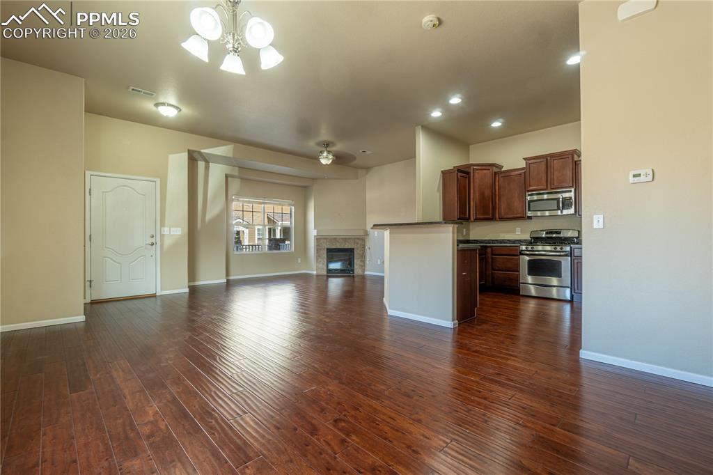 Image 9 of 33: Unfurnished living room with a fireplace, dark wood-style flooring, a ceili