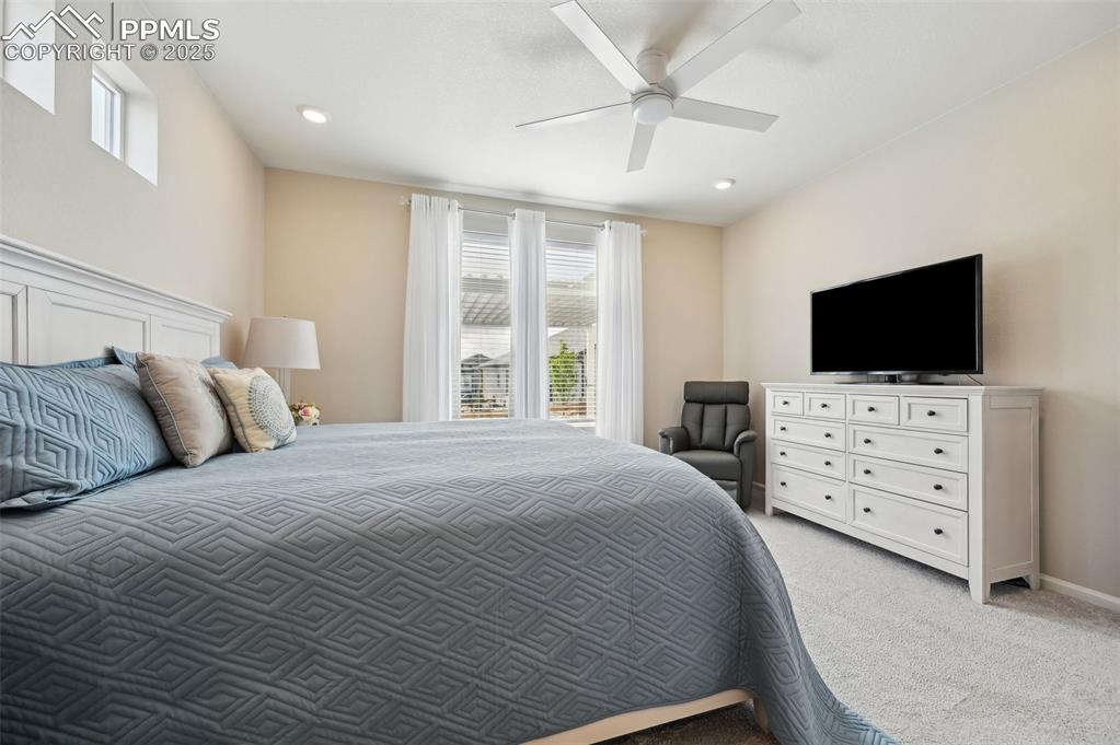 Image 17 of 44: Bedroom with light colored carpet, multiple windows, recessed lighting, and