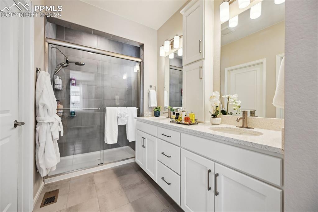 Image 20 of 44: Bathroom featuring a stall shower, tile patterned floors, and double vanity