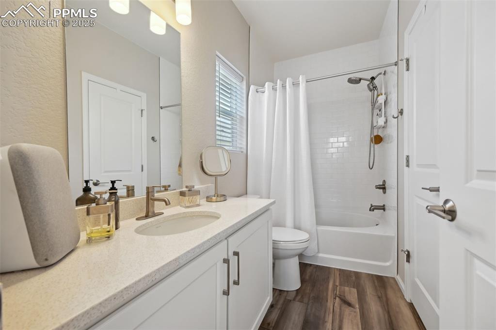 Image 23 of 44: Bathroom with wood finished floors, toilet, vanity, and shower / tub combo