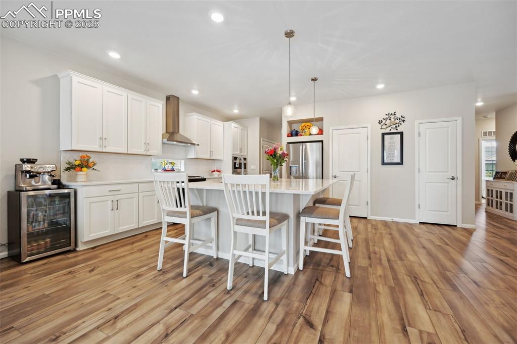 Image 8 of 44: Kitchen featuring stainless steel fridge, wine cooler, wall chimney exhaust