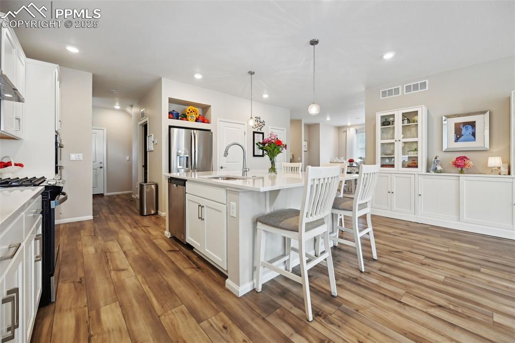 Image 9 of 44: Kitchen with stainless steel appliances, a sink, a breakfast bar, white cab