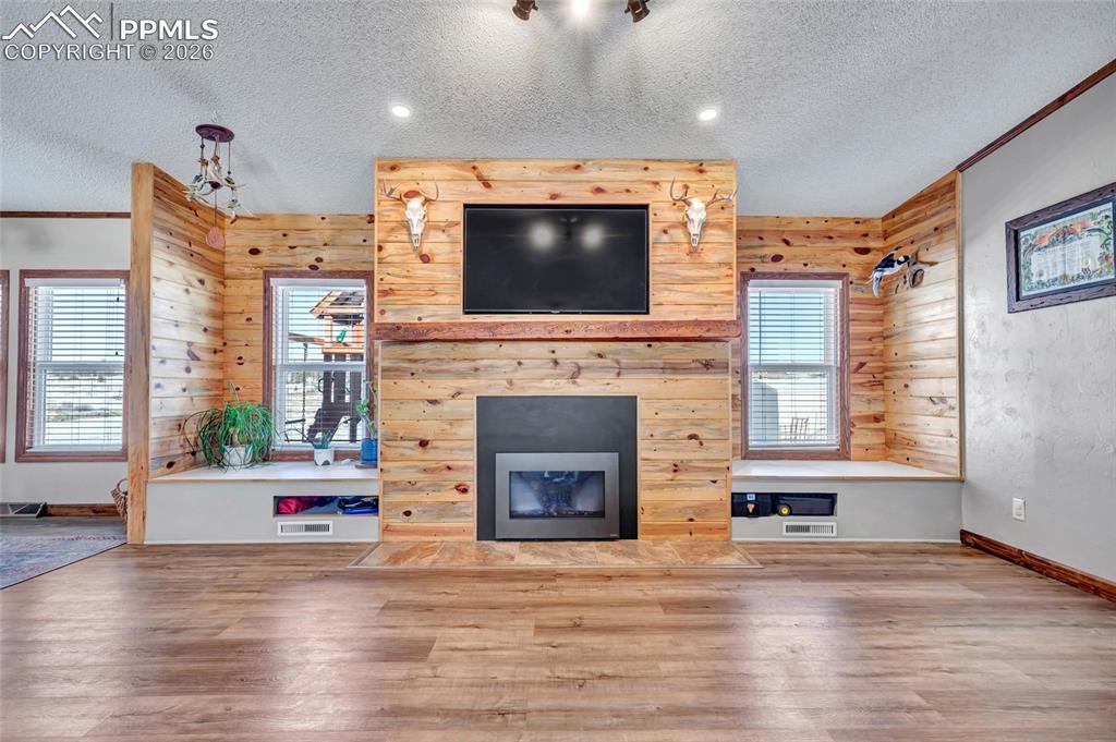 Image 12 of 36: Unfurnished living room with a fireplace with flush hearth, a textured ceil