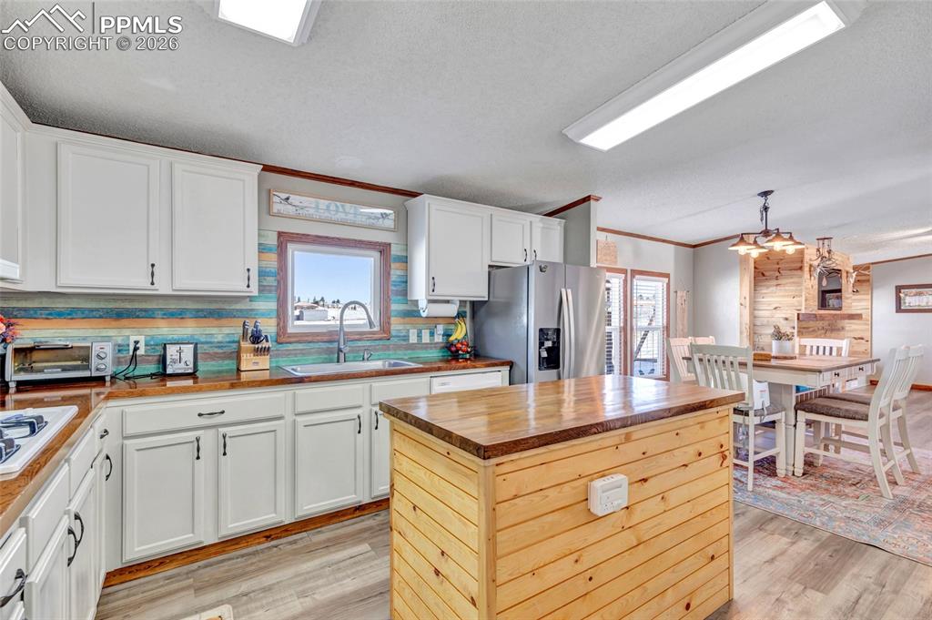 Image 18 of 36: Kitchen with butcher block counters, a kitchen island, crown molding, a tex