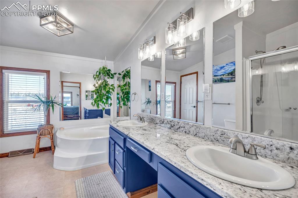 Image 21 of 36: Bathroom with a stall shower, a garden tub, double vanity, and light tile p