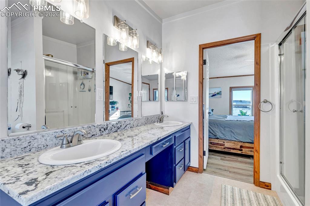 Image 23 of 36: Full bath with a shower stall, ensuite bathroom, double vanity, and crown m