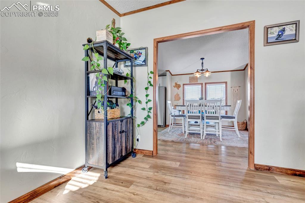 Image 26 of 36: Dining room featuring ornamental molding, wood finished floors, and a chand