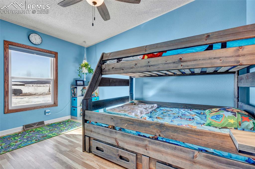 Image 29 of 36: Bedroom with a textured ceiling, light wood-style floors, a ceiling fan, an