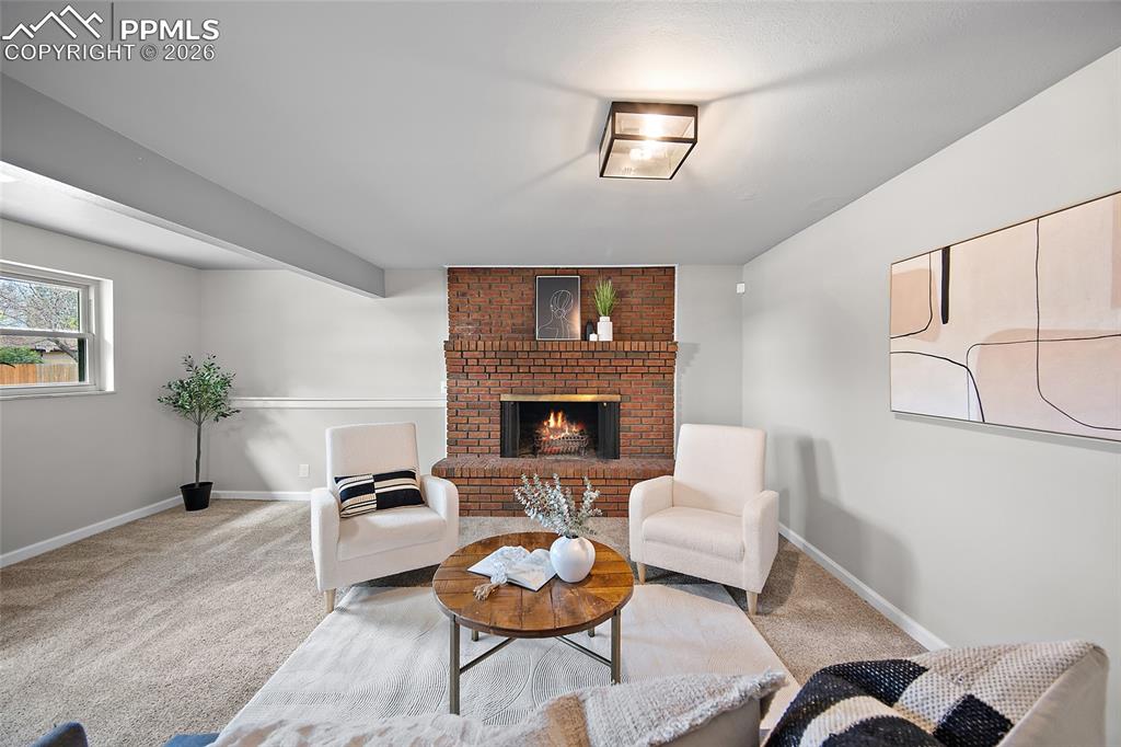 Image 27 of 38: Carpeted living area with a fireplace and baseboards