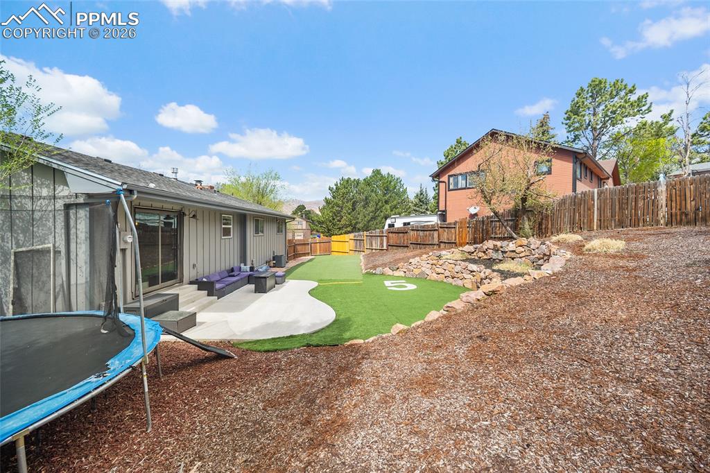 Image 32 of 38: Fenced backyard featuring a patio, a trampoline and turf