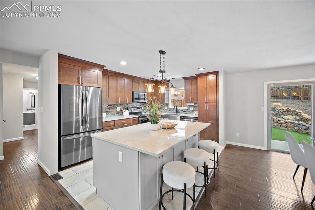Image 6 of 38: Kitchen featuring stainless steel appliances, a center island, dark wood-ty