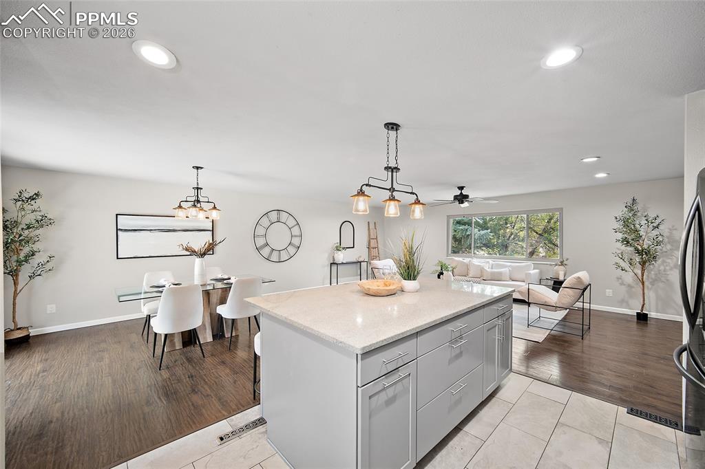 Image 7 of 38: Kitchen featuring gray cabinets, a kitchen island, decorative light fixture