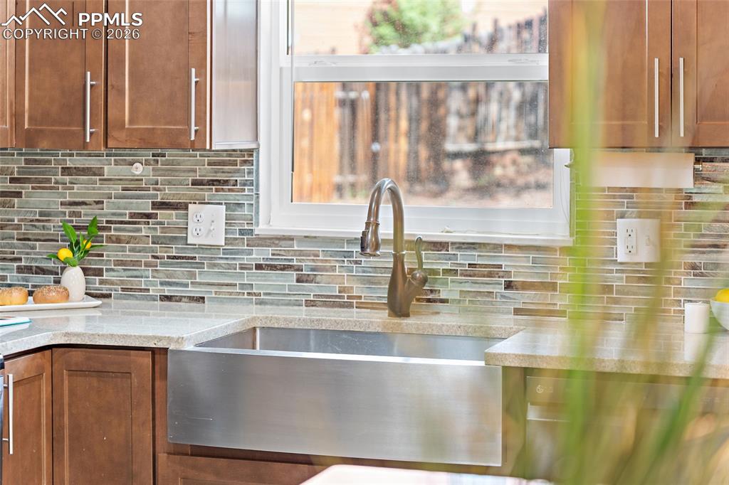 Image 8 of 38: Kitchen with light stone countertops and wood finish cabinetry