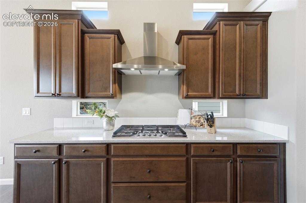 Image 10 of 45: Enjoy the gas cook top with vent and cherry cabinetry