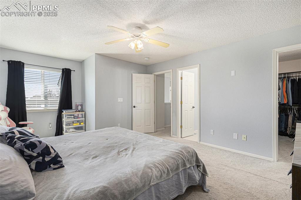 Image 10 of 21: Carpeted bedroom featuring a textured ceiling, a closet, a ceiling fan, a s