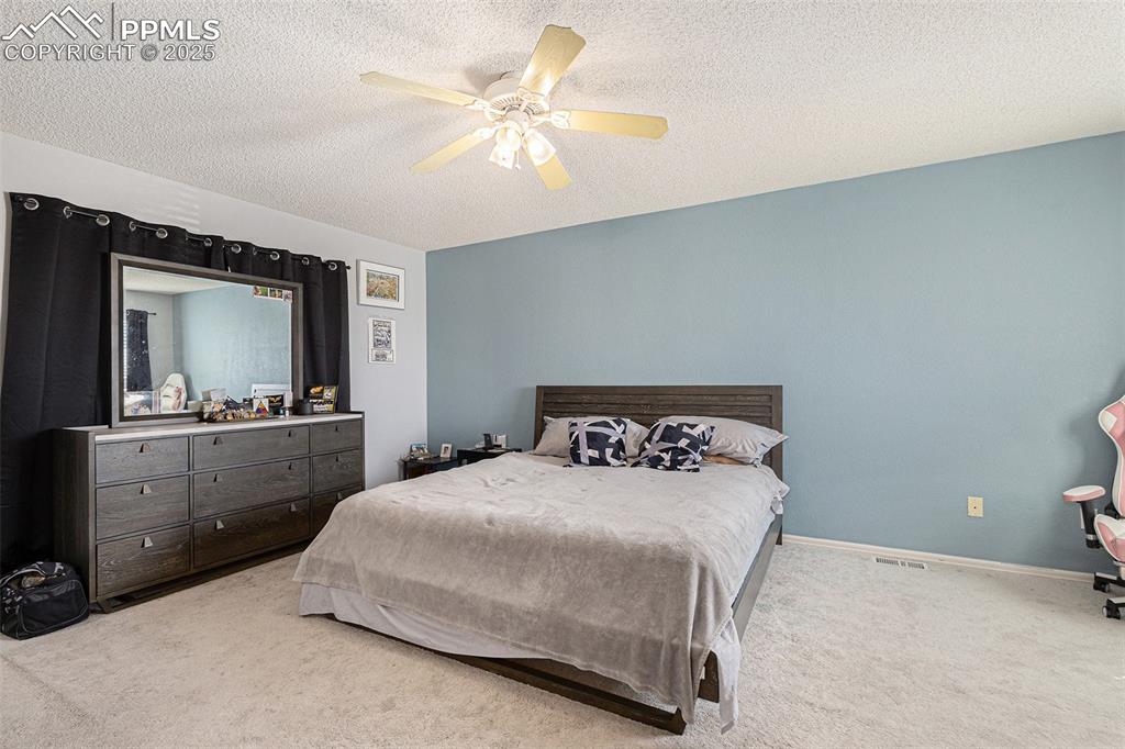 Image 11 of 21: Carpeted bedroom featuring baseboards, a textured ceiling, and a ceiling fa