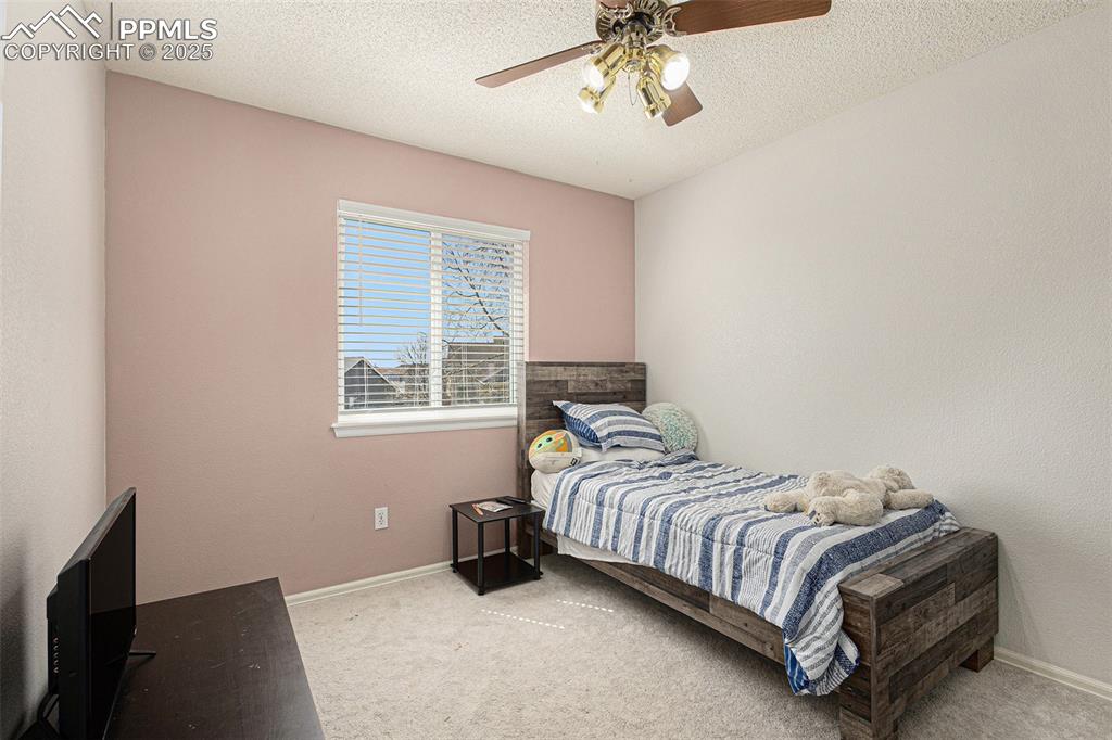 Image 14 of 21: Carpeted bedroom featuring baseboards, a ceiling fan, and a textured ceilin