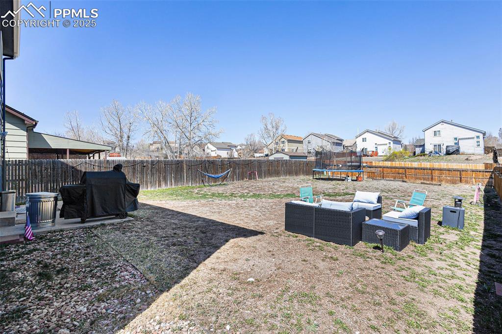Image 19 of 21: View of yard with a trampoline, a residential view, a fenced backyard, and 