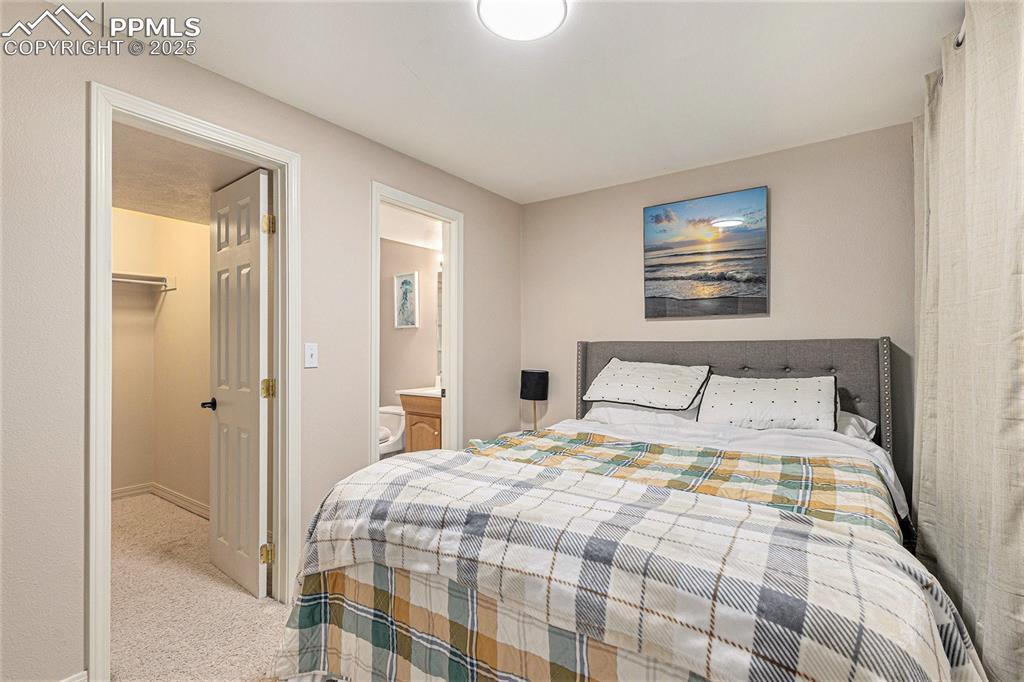 Image 7 of 21: Carpeted bedroom featuring ensuite bathroom, baseboards, and a spacious clo