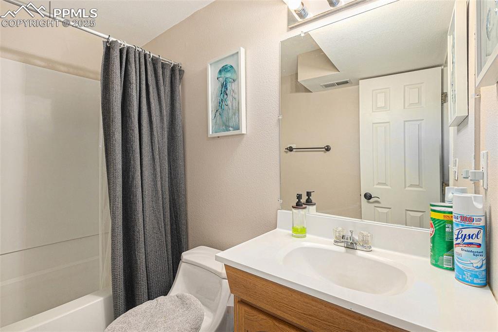 Image 8 of 21: Bathroom with shower / bath combination with curtain, vanity, visible vents