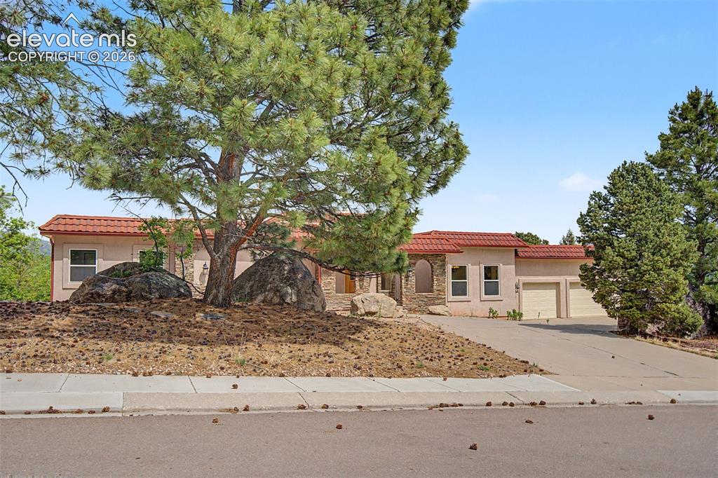 Image 1 of 50: Raised ranch design nestled among mature pines and natural rock outcropping