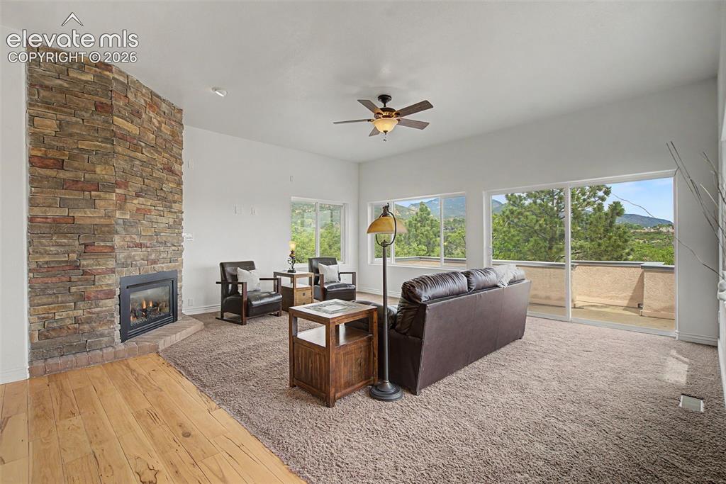 Image 12 of 50: Formal living room with gas fireplace, mountain views, and deck access
