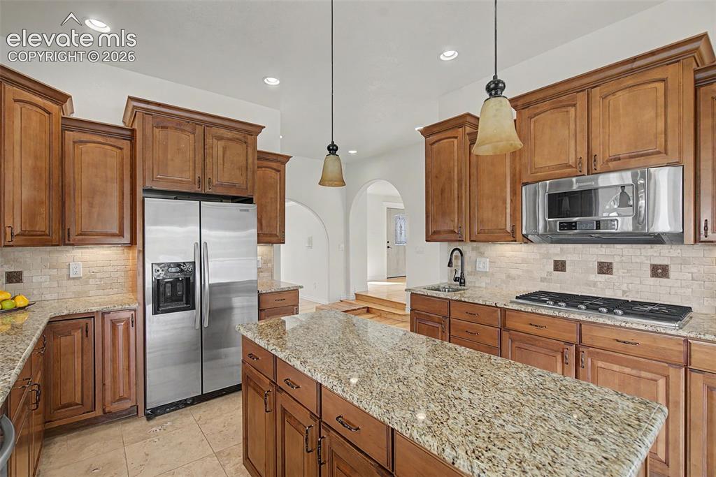 Image 16 of 50: Spacious kitchen with granite surfaces, stainless steel appliances, and abu
