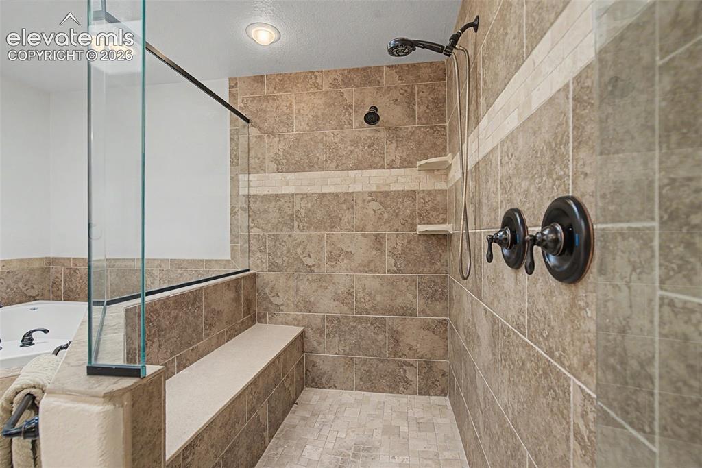 Image 25 of 50: Oversized walk-in shower with bench seating and tile surround
