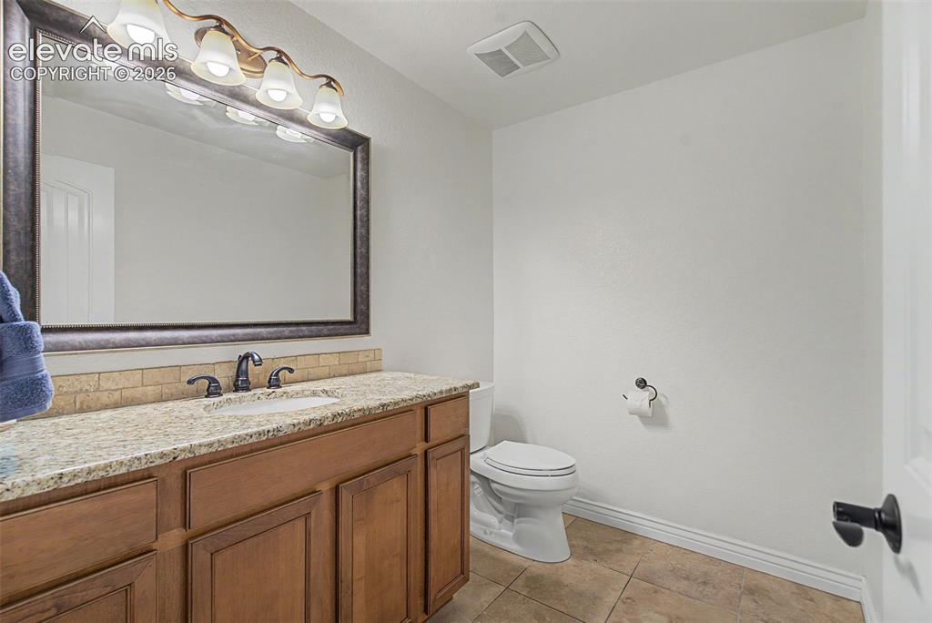 Image 30 of 50: Convenient main-level powder room with granite countertop and maple vanity