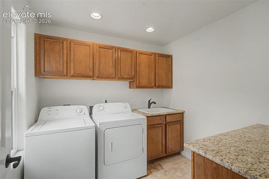 Image 31 of 50: Oversized laundry room with utility sink, folding counter, and extensive ca