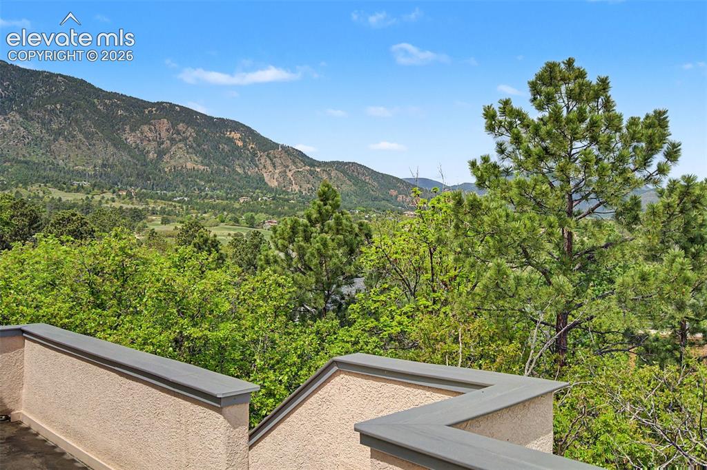Image 45 of 50: Mountain and golf course surroundings framed by mature trees and natural la