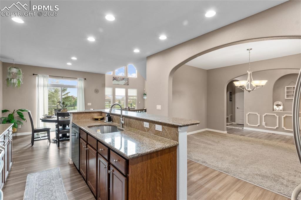 Image 10 of 36: Kitchen featuring arched walkways, light wood-style floors, light stone cou