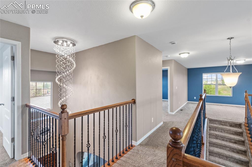 Image 13 of 36: Hallway featuring carpet floors, a chandelier, and an upstairs landing
