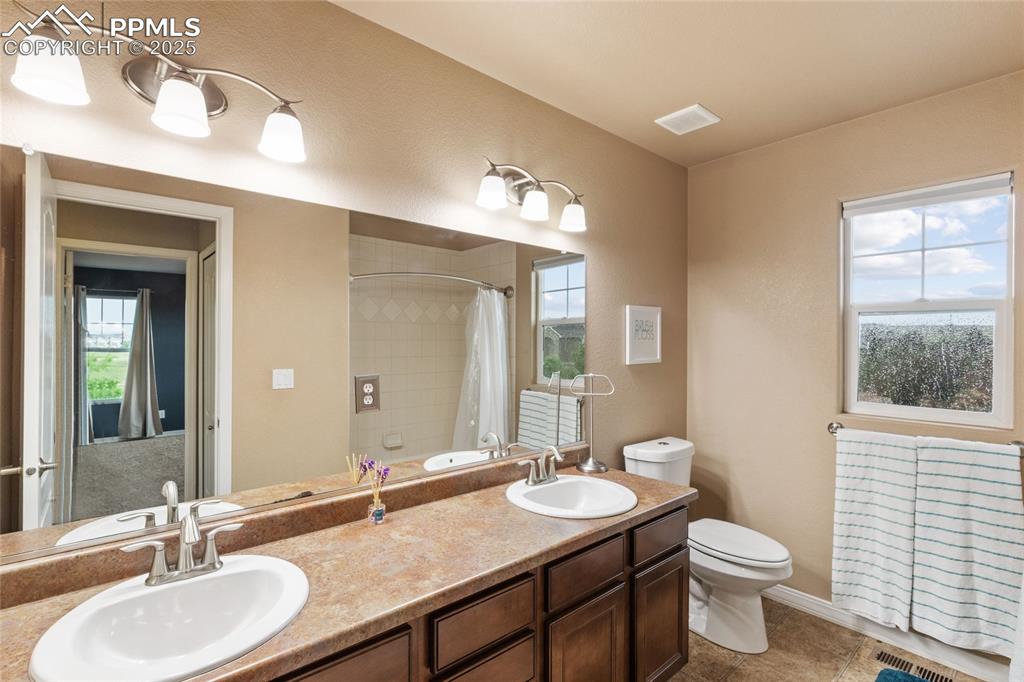Image 19 of 36: Bathroom featuring plenty of natural light, double vanity, and tile pattern