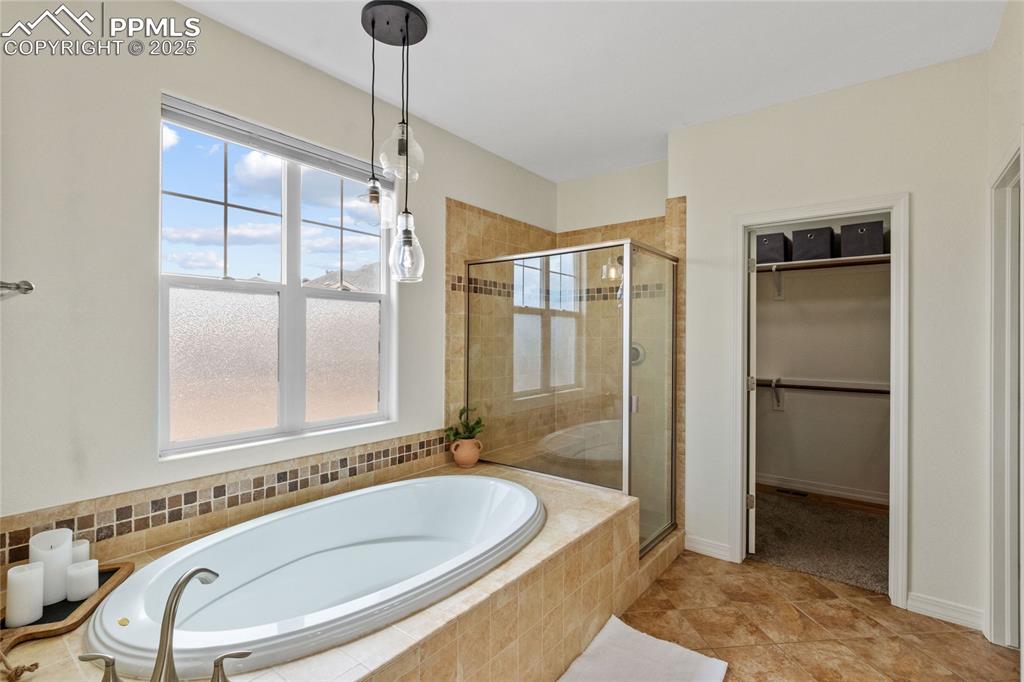 Image 24 of 36: Full bathroom with a shower stall, a bath, and a spacious closet