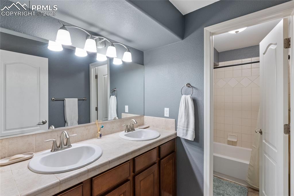 Image 30 of 36: Full bathroom featuring double vanity and washtub / shower combination