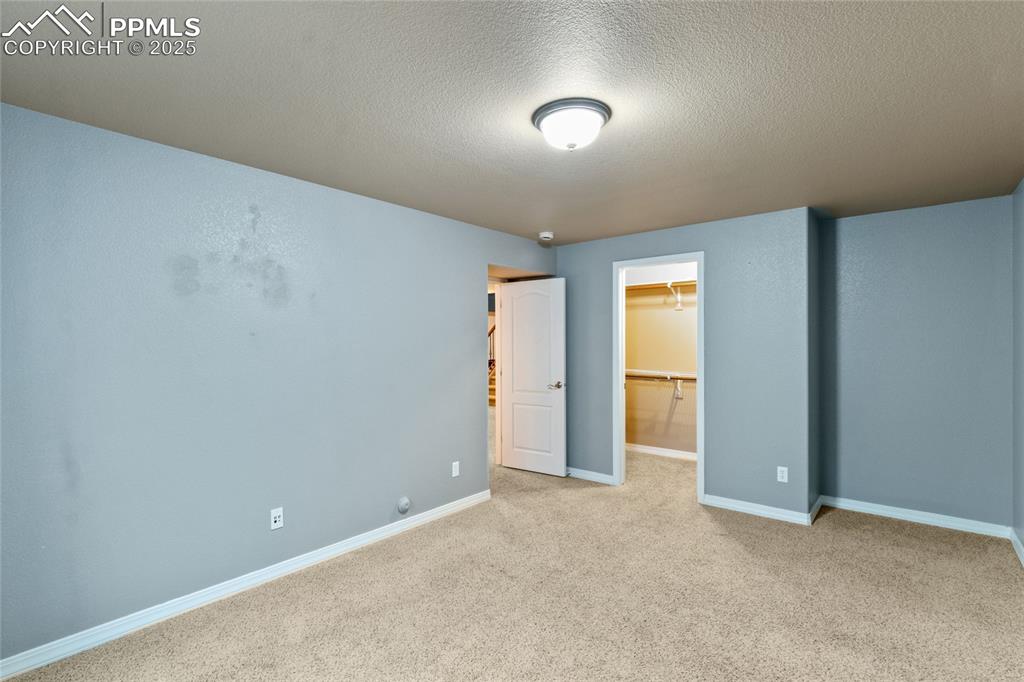 Image 31 of 36: Unfurnished bedroom featuring carpet, a textured ceiling, a spacious closet