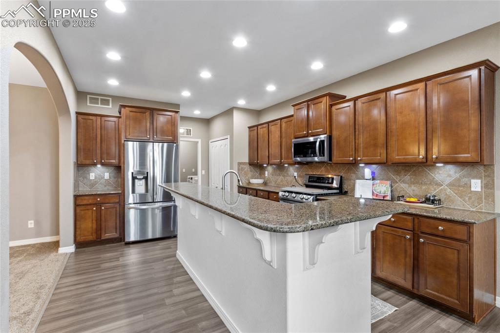 Image 9 of 36: Kitchen featuring stainless steel appliances, a kitchen breakfast bar, brow