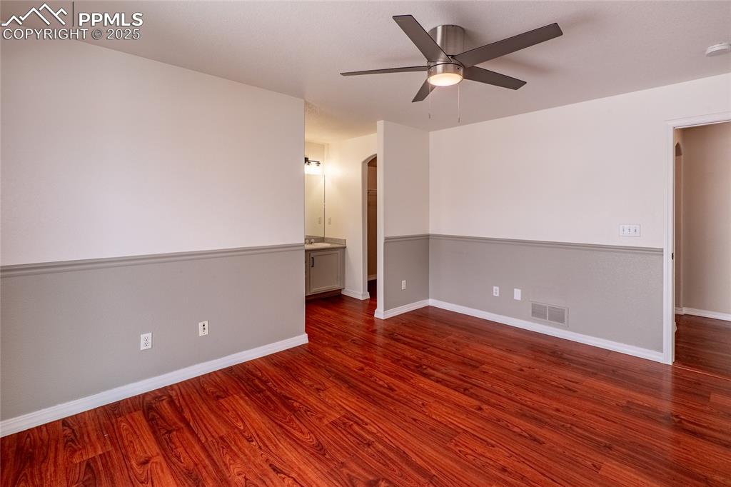 Image 15 of 47: Spare room with arched walkways, dark wood-style flooring, and ceiling fan