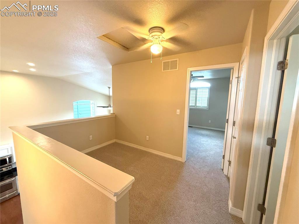 Image 31 of 47: Hallway featuring a textured ceiling, carpet flooring, an upstairs landing,
