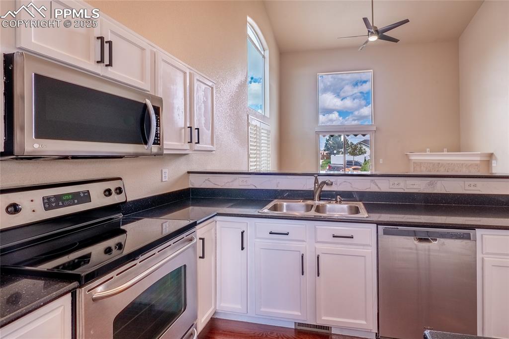 Image 7 of 47: Kitchen with stainless steel appliances, white cabinets, healthy amount of
