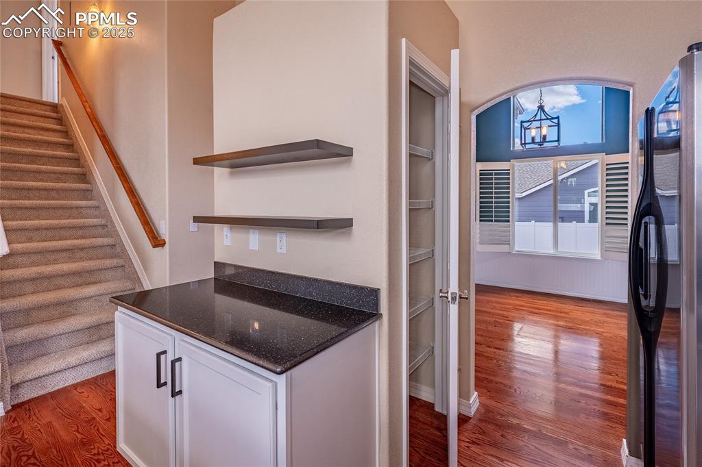 Image 8 of 47: Kitchen with dark wood-style flooring, white cabinetry, open shelves, frees