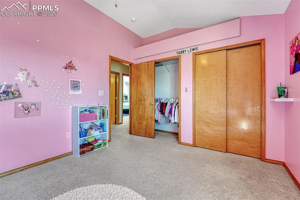 Image 24 of 40: Upstairs room featuring soft pink walls, sloped ceiling, and neutral carpet