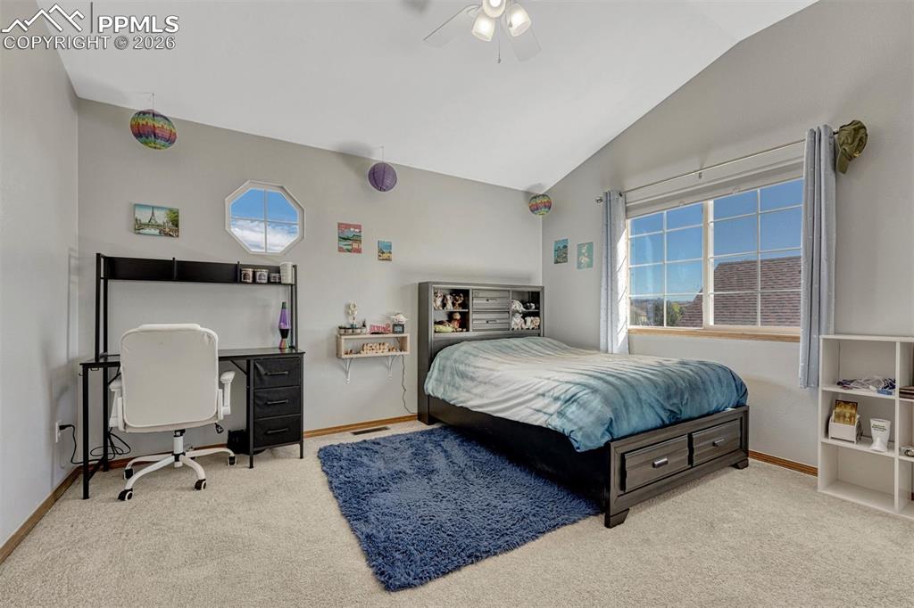 Image 25 of 40: Upstairs bedroom featuring light-colored carpeting, a vaulted ceiling, and 