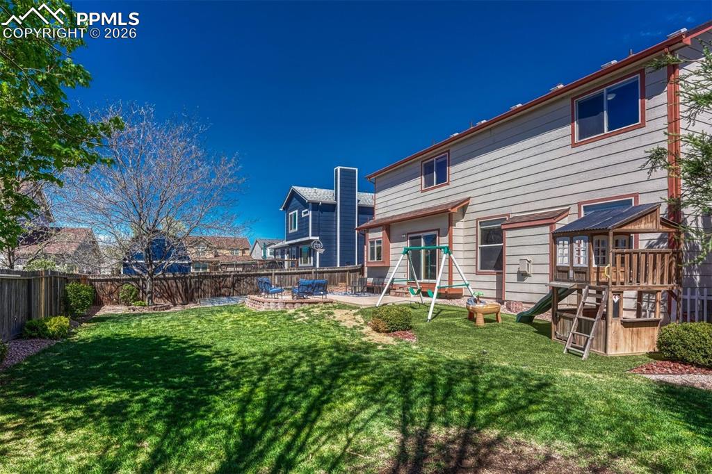 Image 38 of 40: Expansive backyard with a manicured lawn, established trees, and a wooden p