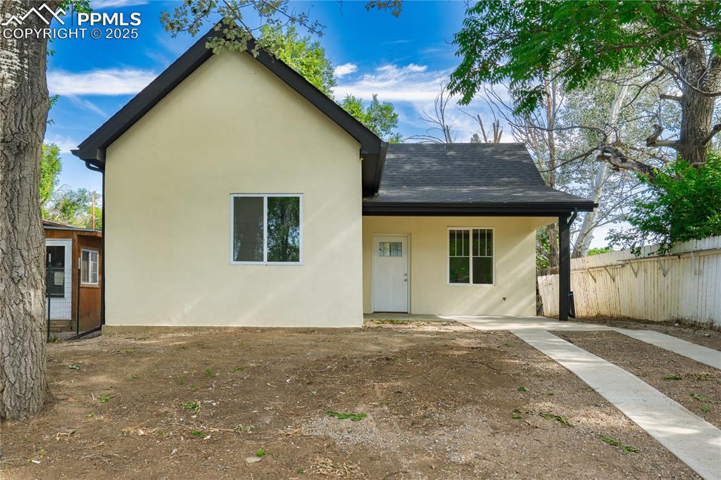 Caption: View of front of property with a shingled roof and stucco siding