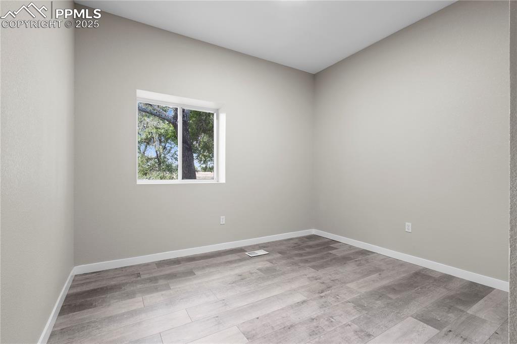 Image 18 of 25: Unfurnished room with wood finished floors and baseboards